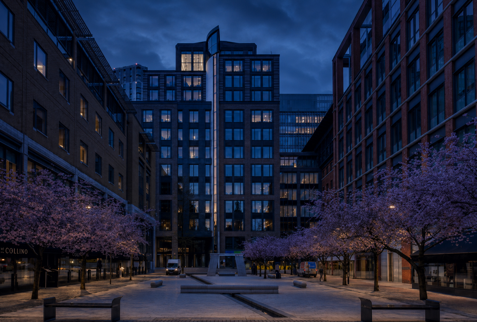 Modern UK commercial development at blue hour, warm interior lights reflected in a canal
